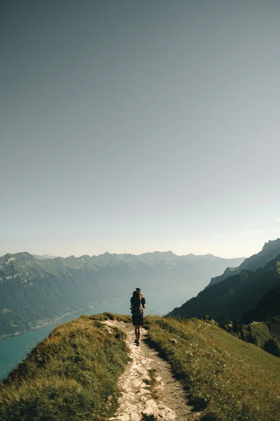 A runner following a mountain trail above a lake