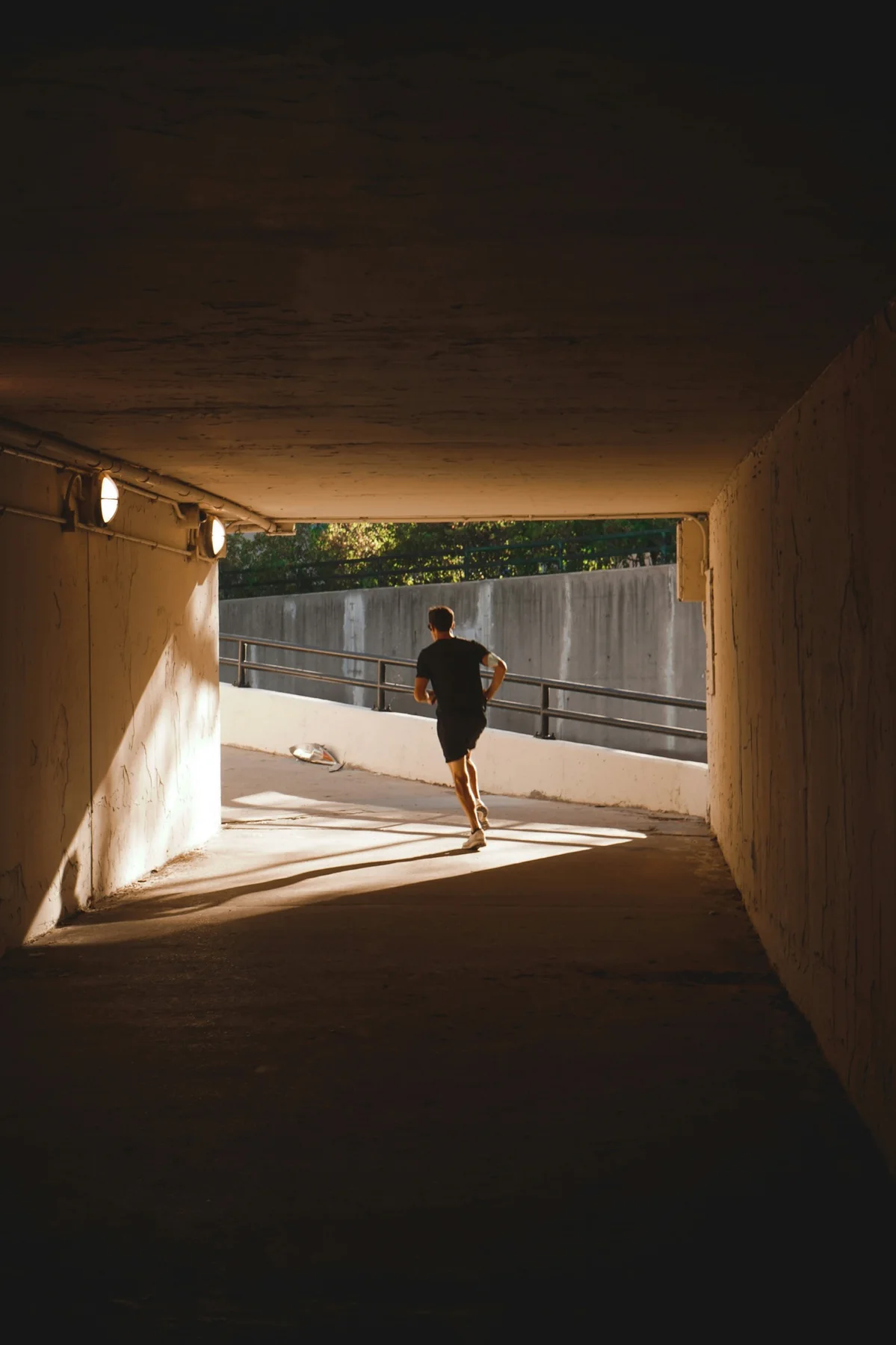 A runner leaving an underpass in the morning light